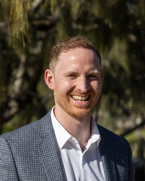 Sam McManus, clinical lead at Kensington Square Therapy, smiling, outdoors in a grey jacket